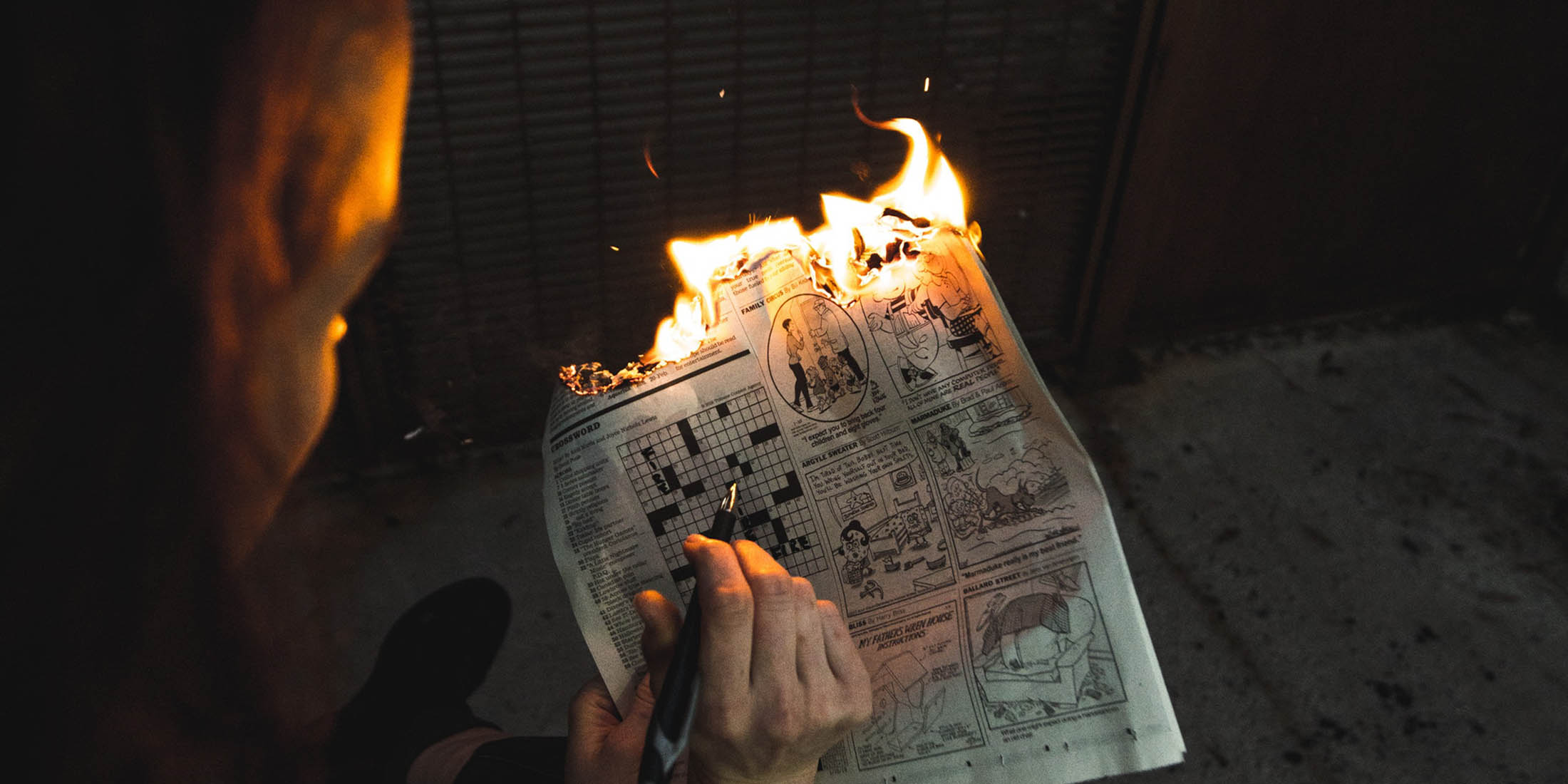 picture of a guy doing a crossword puzzle that is burning